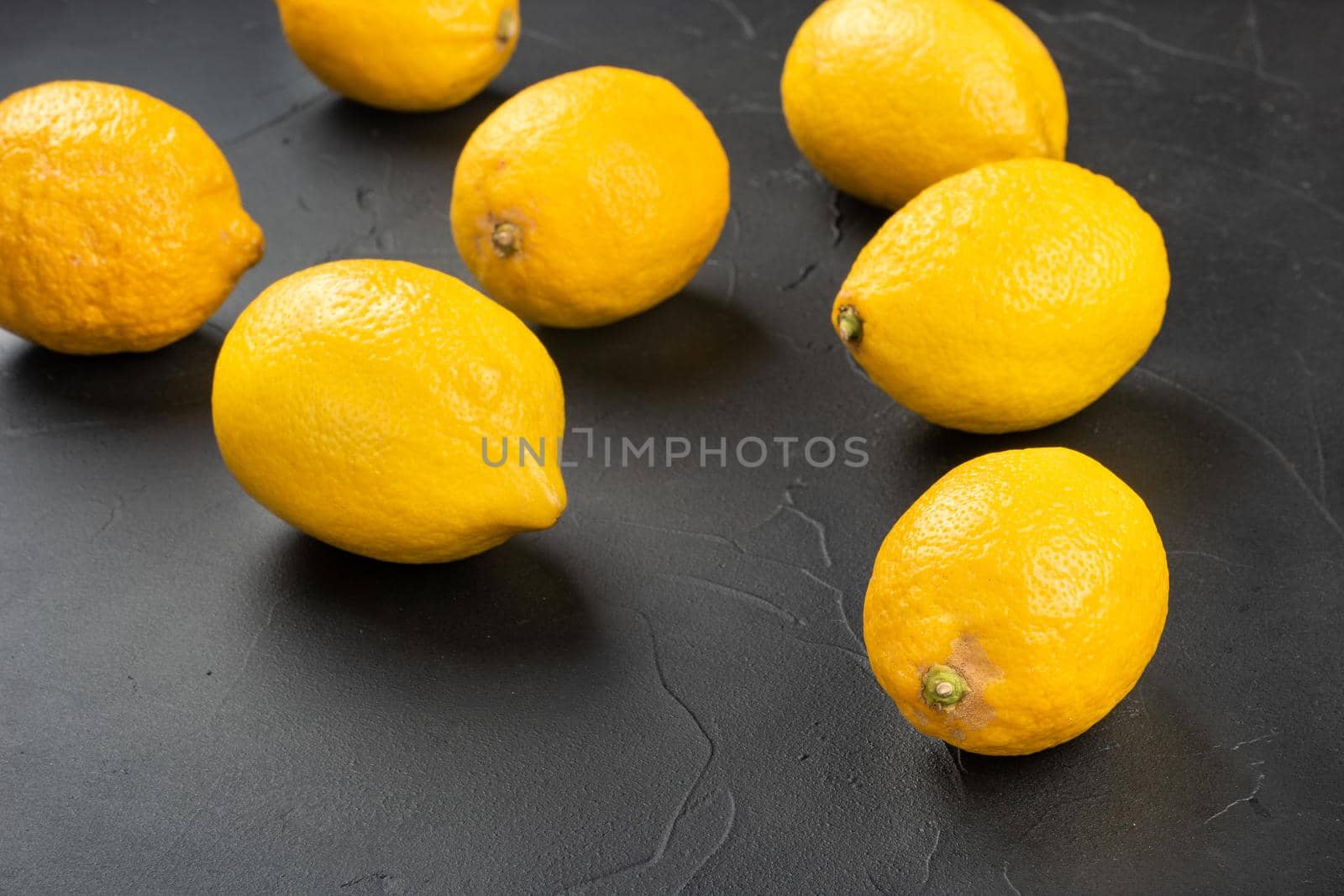 Fresh fruit lemons scattered on a dark concrete background