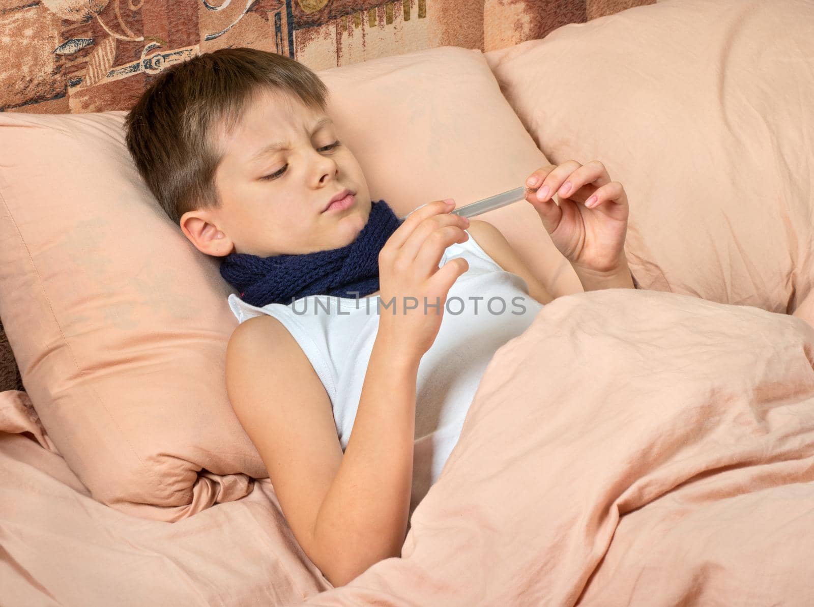 Sick boy in bed watching the temperature on the thermometer