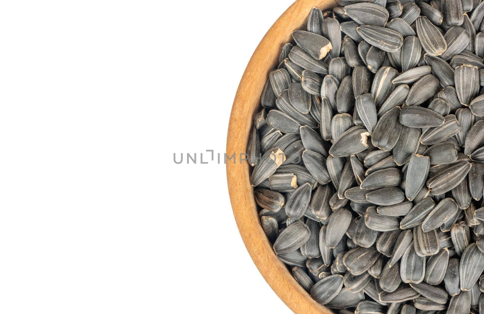 Part of a bowl with sunflower seeds on a white background, top view