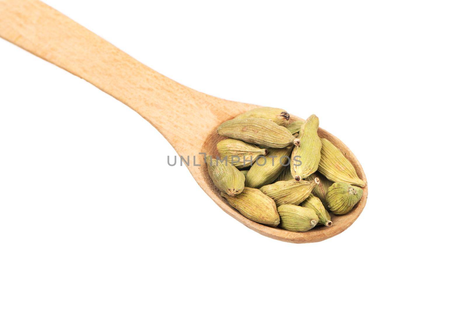 Wooden spoon with dry green cardamom closeup on white background