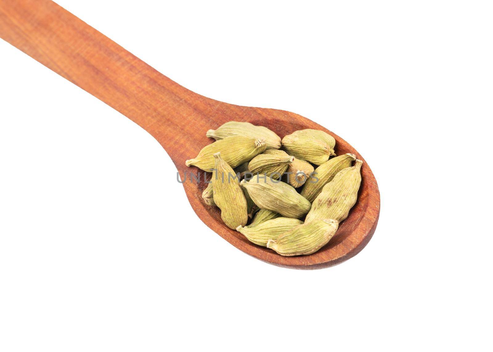 Green cardamom in wooden spoon closeup on white background