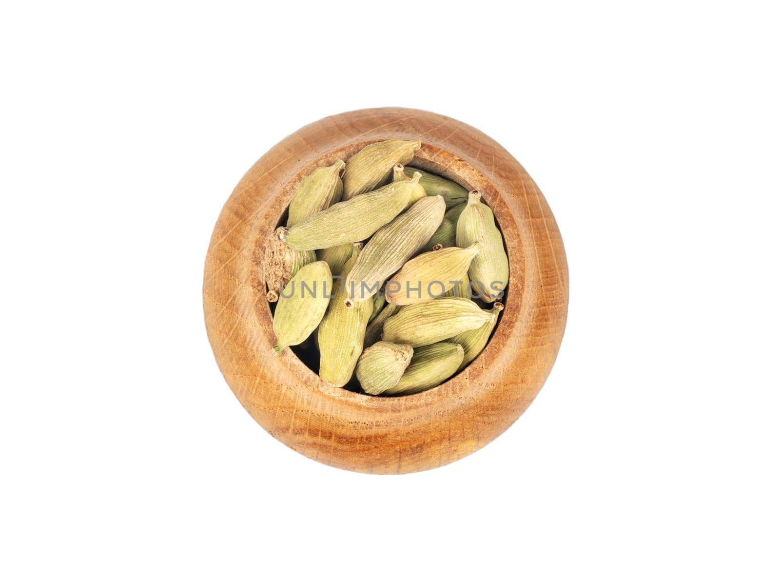 Dry green cardamom in wooden container on white background, top view