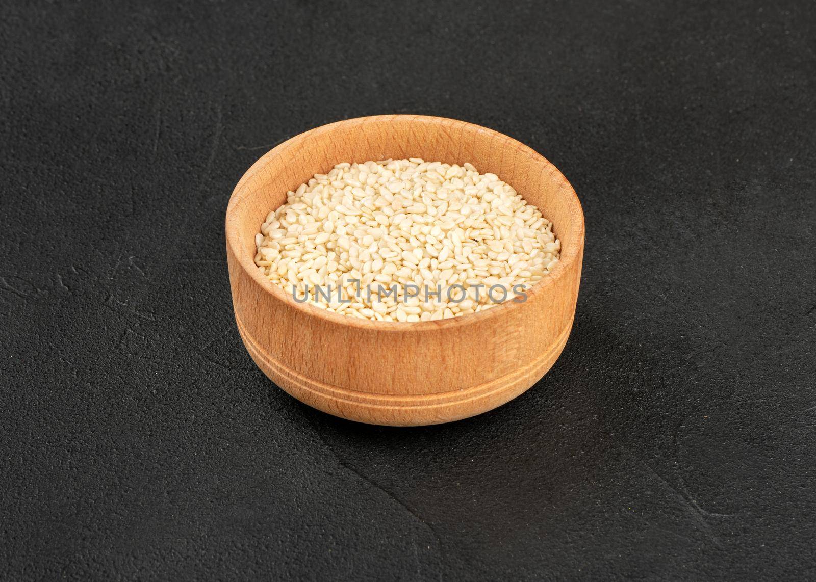 Sesame seeds in a wooden bowl on a dark background
