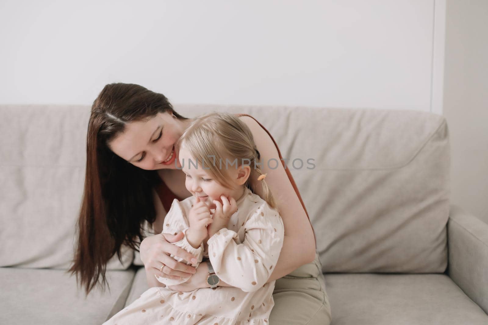 Cute toddler daughter and happy mother in cozy light room at home. Mother's Day love family concept by paralisart