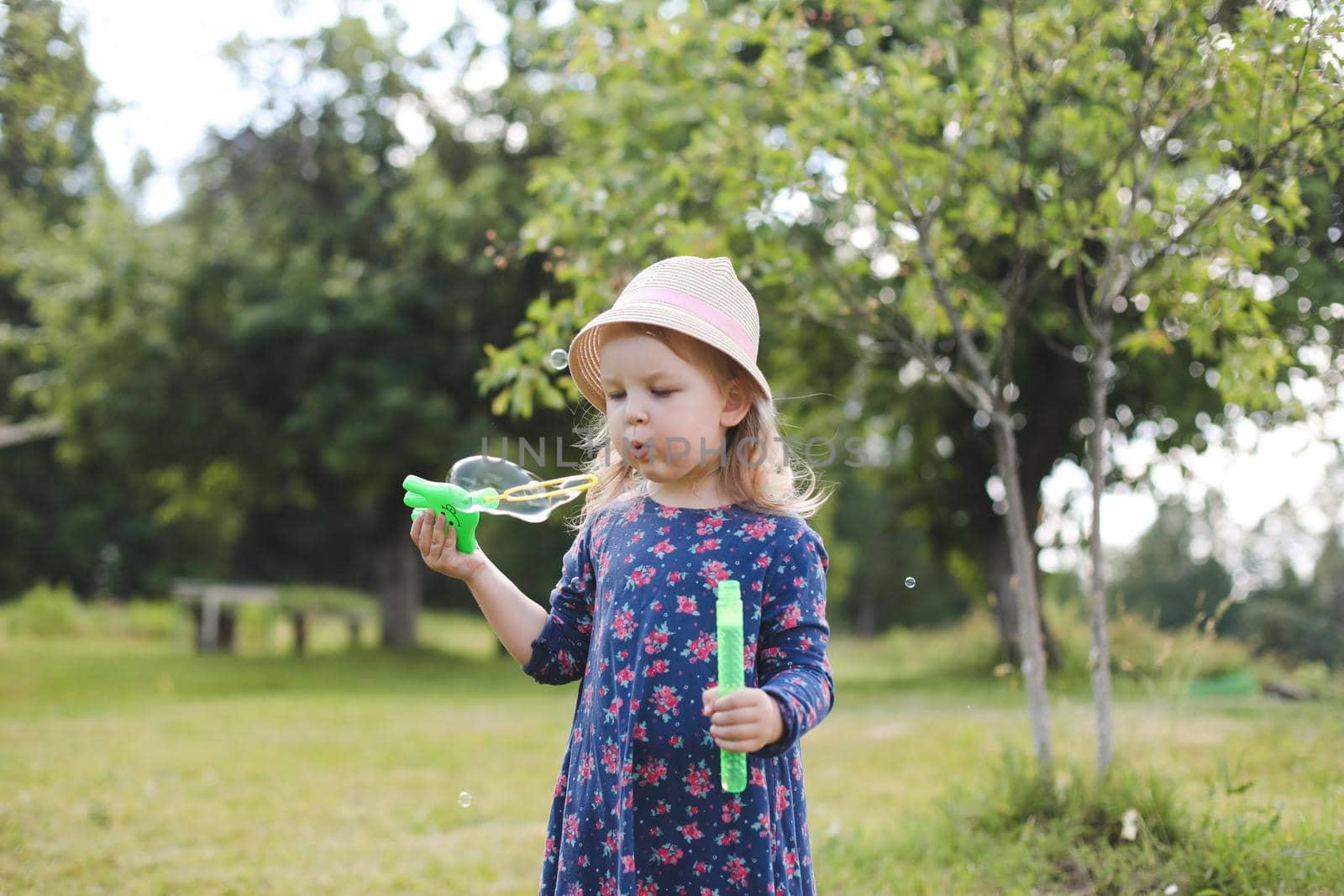 Cute little girl blowing soap bubbles on a walk in summer outdoors.