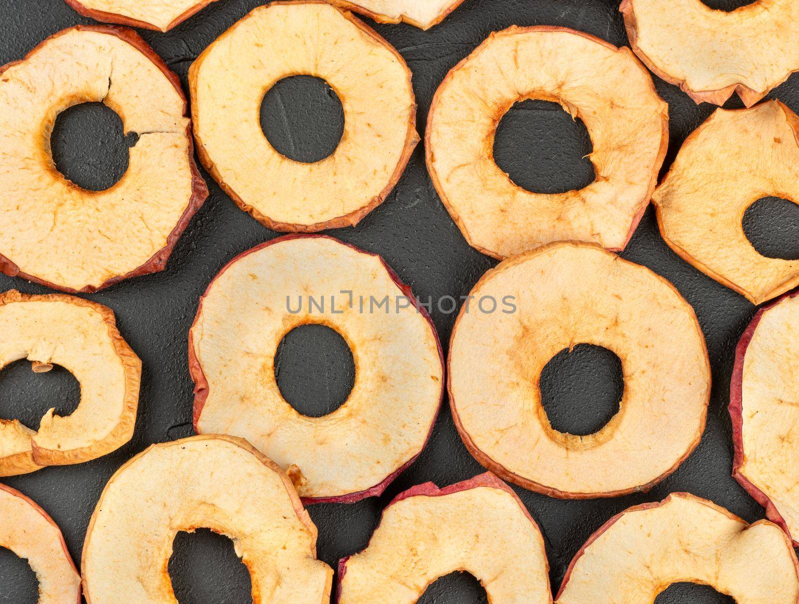 Scattered dry Apple chips on a dark concrete background