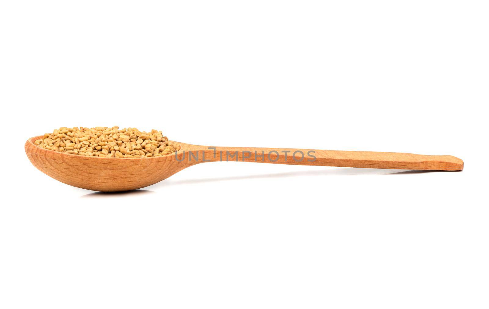 Seeds of fenugreek in wooden spoon on white background