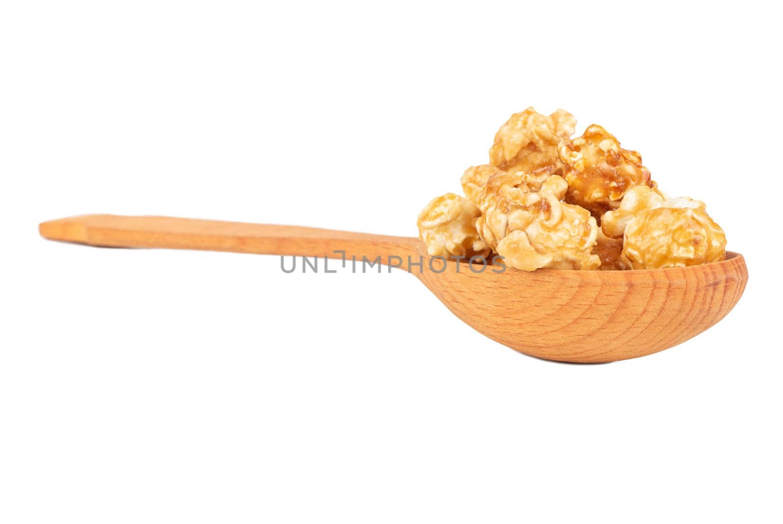 Caramel popcorn in wooden spoon close up on white background