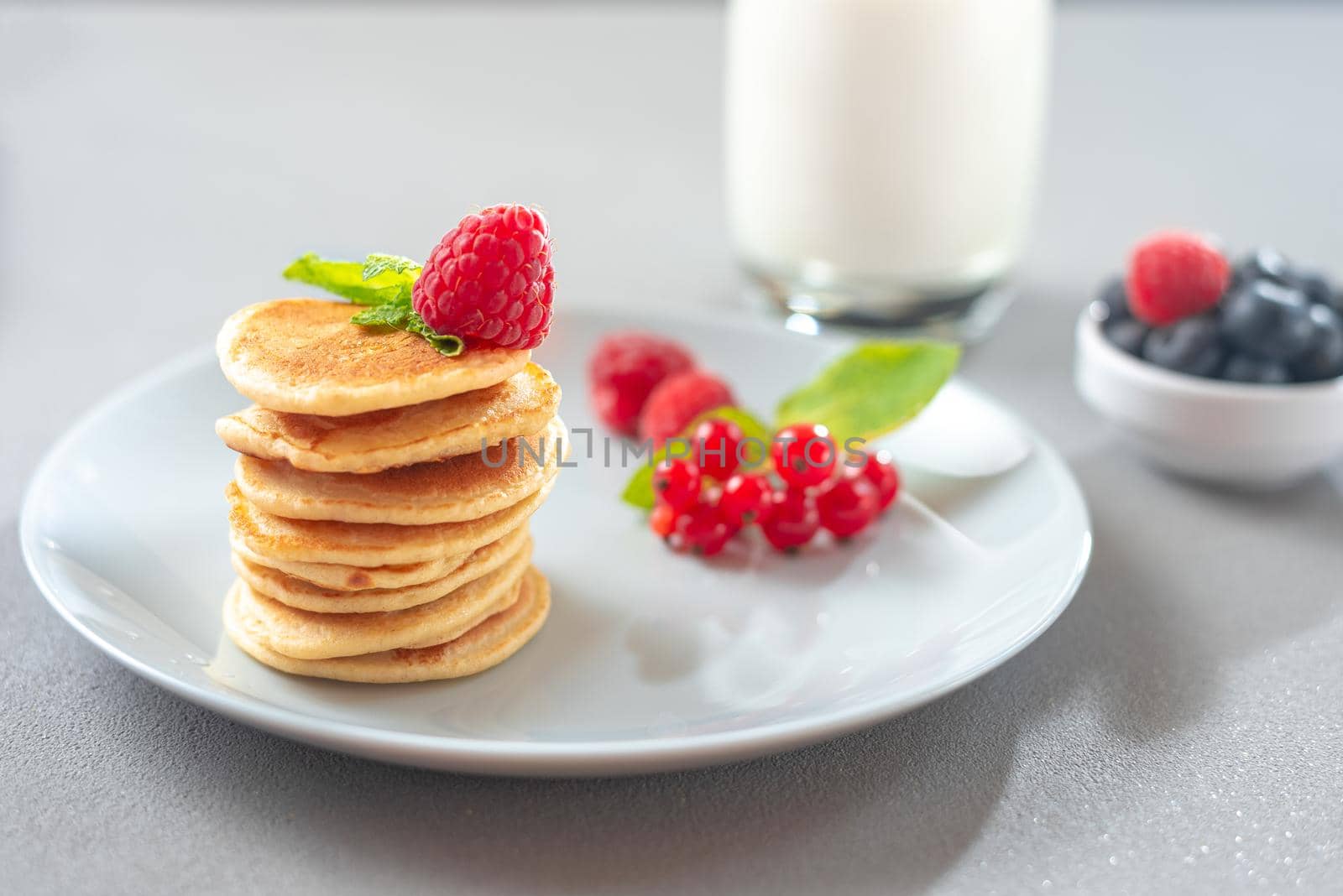 Pancakes with berries on a white plate. American Pancake Mini Pancakes with berries by gulyaevstudio