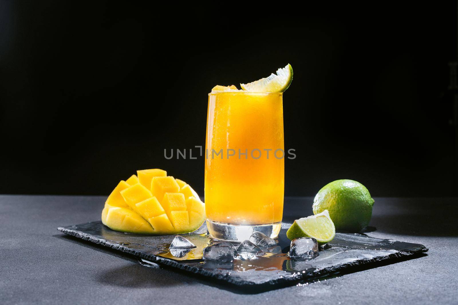 A Mexican smoothie drink made from mango, chili peppers, salt, and lime. A refreshing summer smoothie on a black background of bright orange