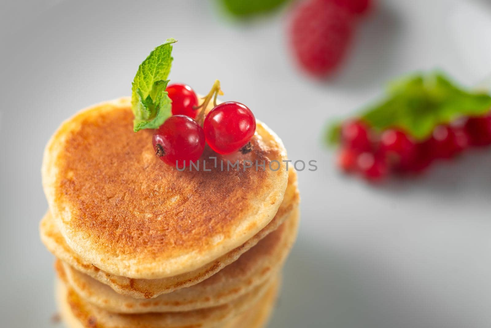 Food for breakfast healthy eating. Pancakes without butter with berries. Food for vegetarians and for dieting. American Pancakes Mini. Mini pancakes with blueberries and raspberries. American breakfast on a dark background. Healthy eating for the whole family. Homemade pancakes with berries.