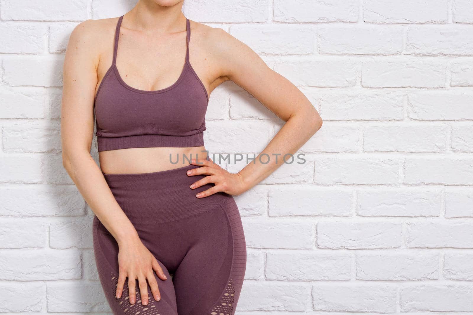 Woman in sportswear posing against white wall made of bricks