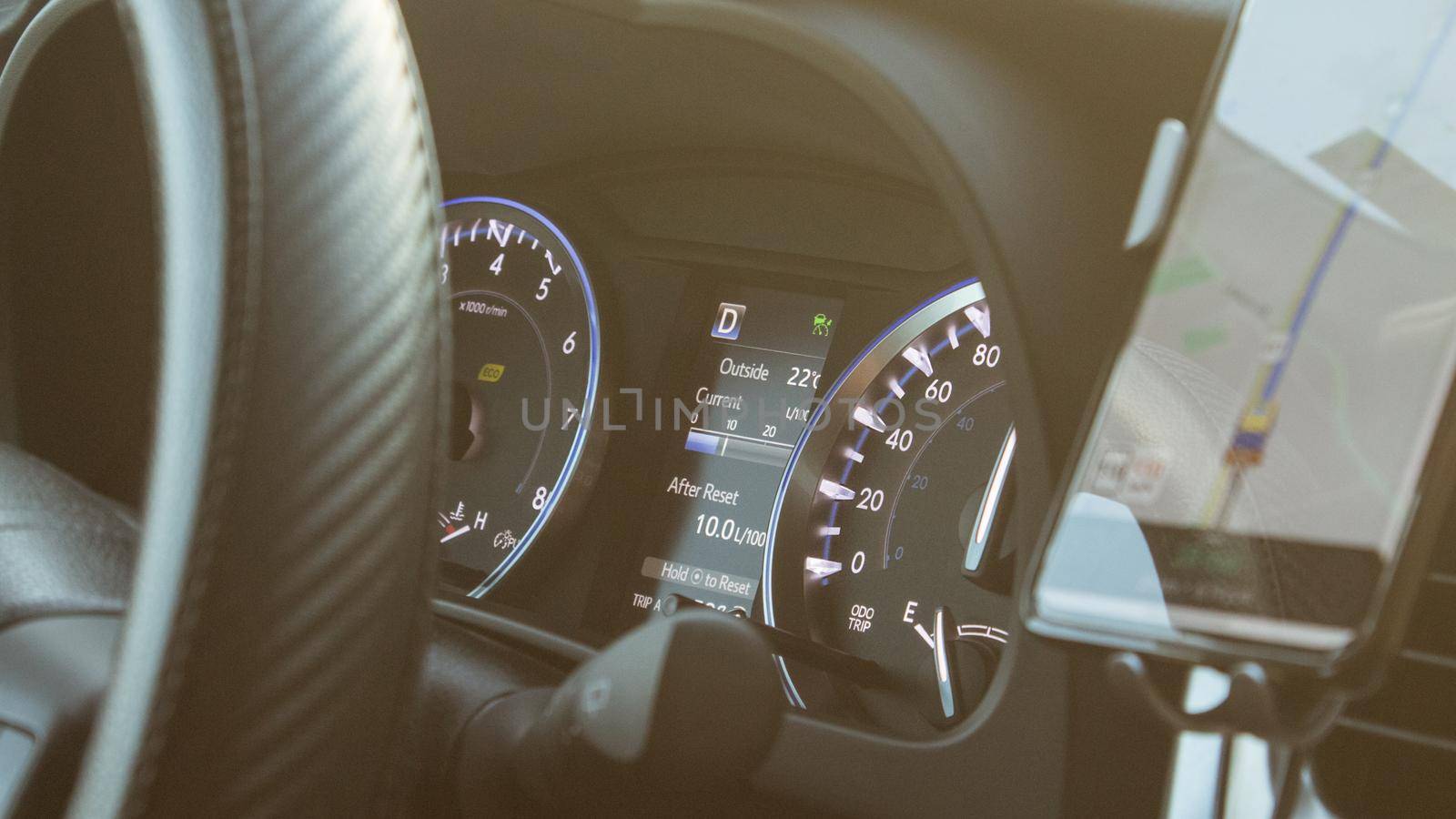 Illuminated speedometer dashboard and steering wheel of a modern car in a sun flare.