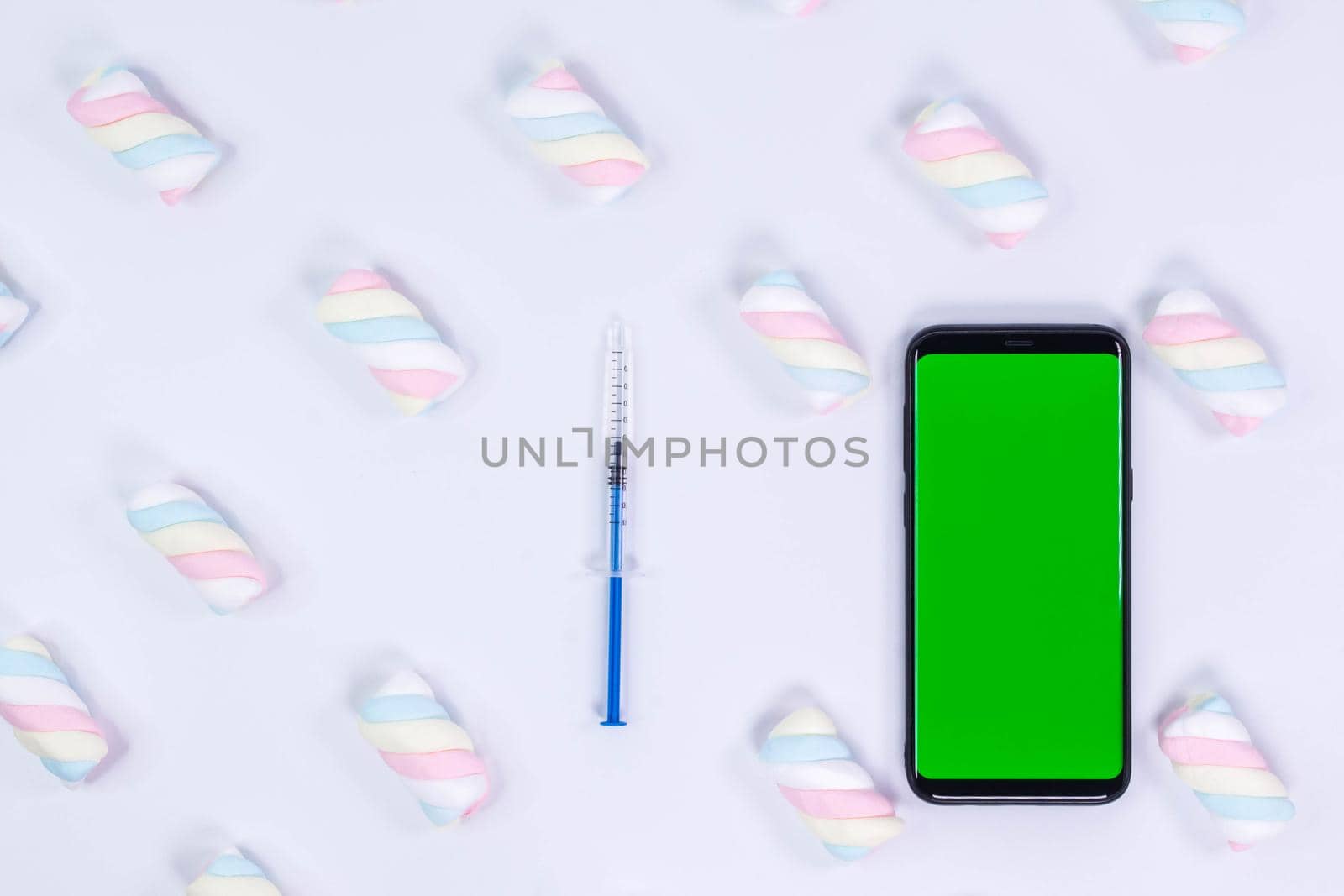 Phone mockup. Syringe with needle and black smartphone with blank screen. White background with twisted marshmallow pattern. Mock up generic device by JuliaDorian