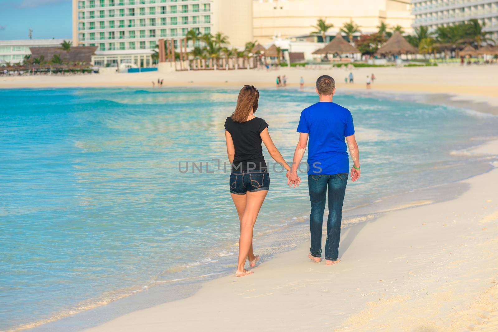 A man and a woman walk on the seashore.