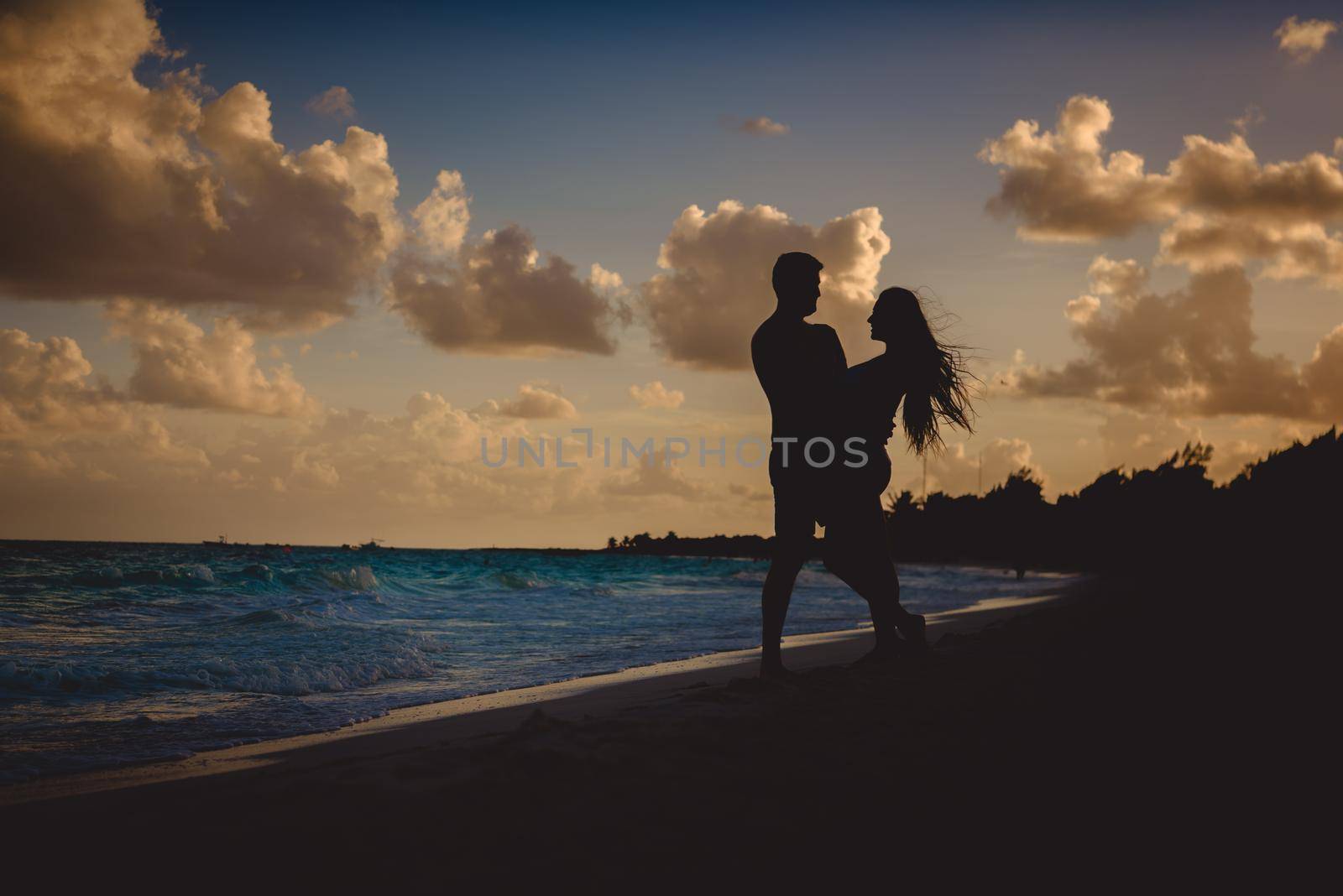 Silhouettes of men and women against the backdrop of the setting sun