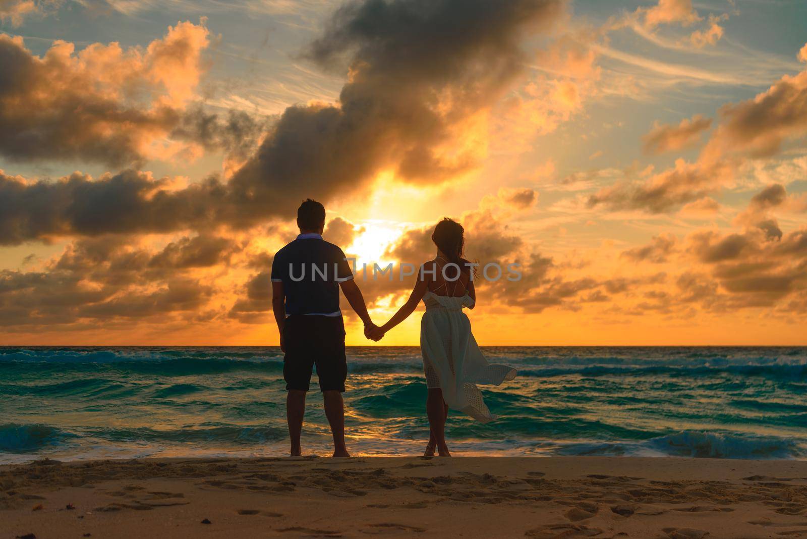 Silhouettes of men and women against the backdrop of the setting sun