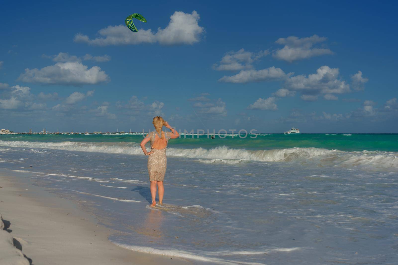 Slender blonde woman admires the sunrise at sea.