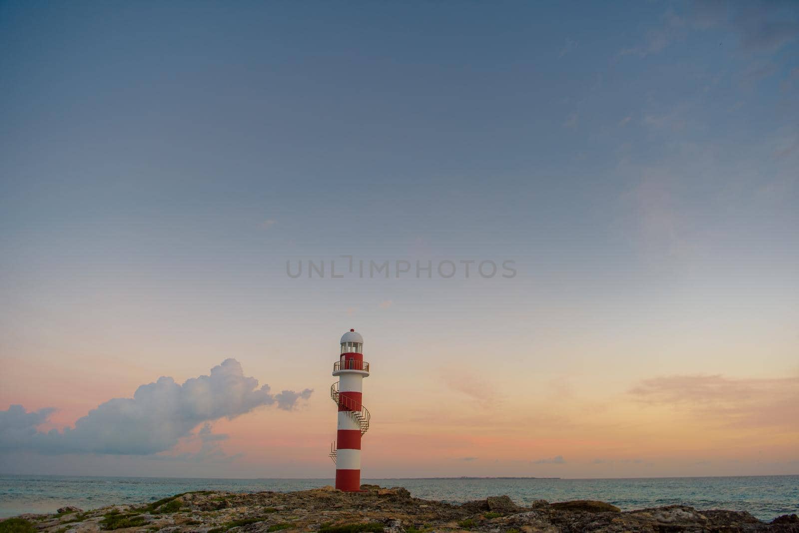 Lighthouse on a rocky shore in Cancun. Clear sky and blue sea.