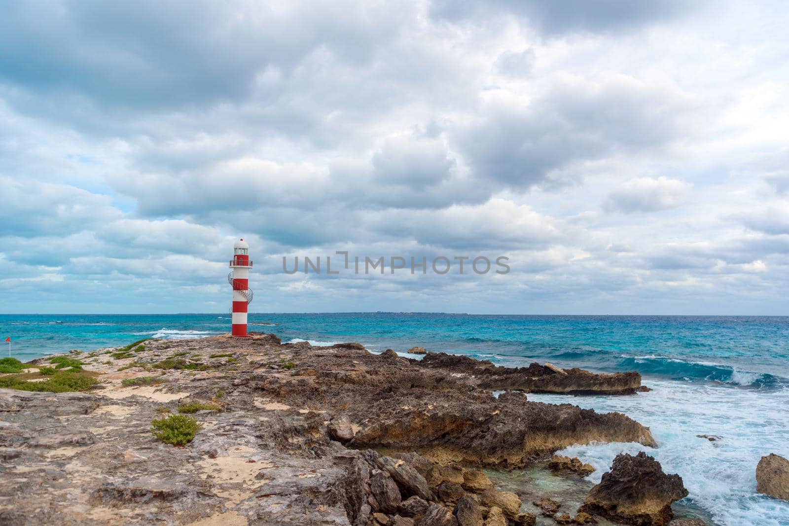 Lighthouse on a rocky shore in Cancun. Clear sky and blue sea.