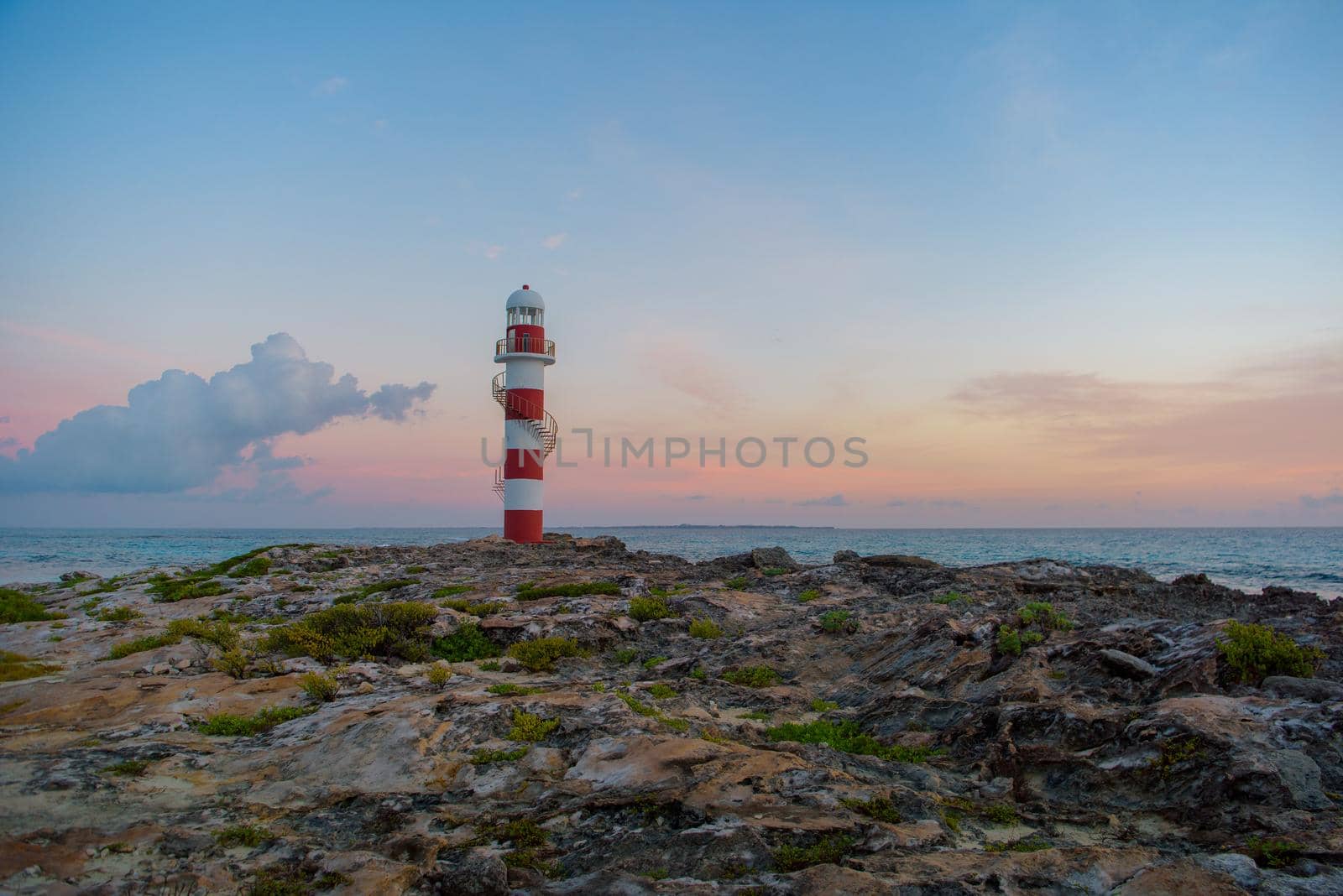 Lighthouse on a rocky shore in Cancun. Clear sky and blue sea.