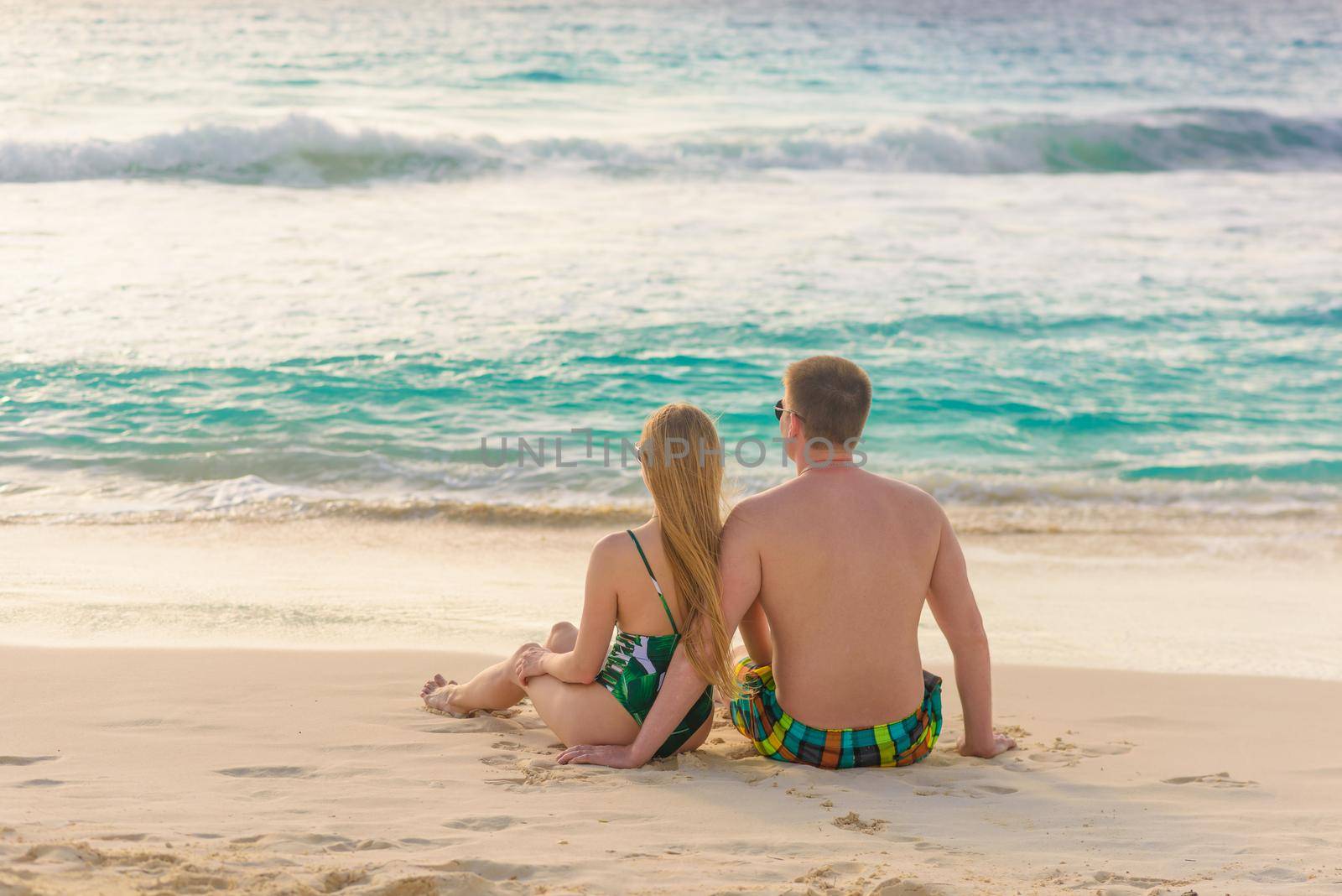 A man and a woman are sitting on the seashore.