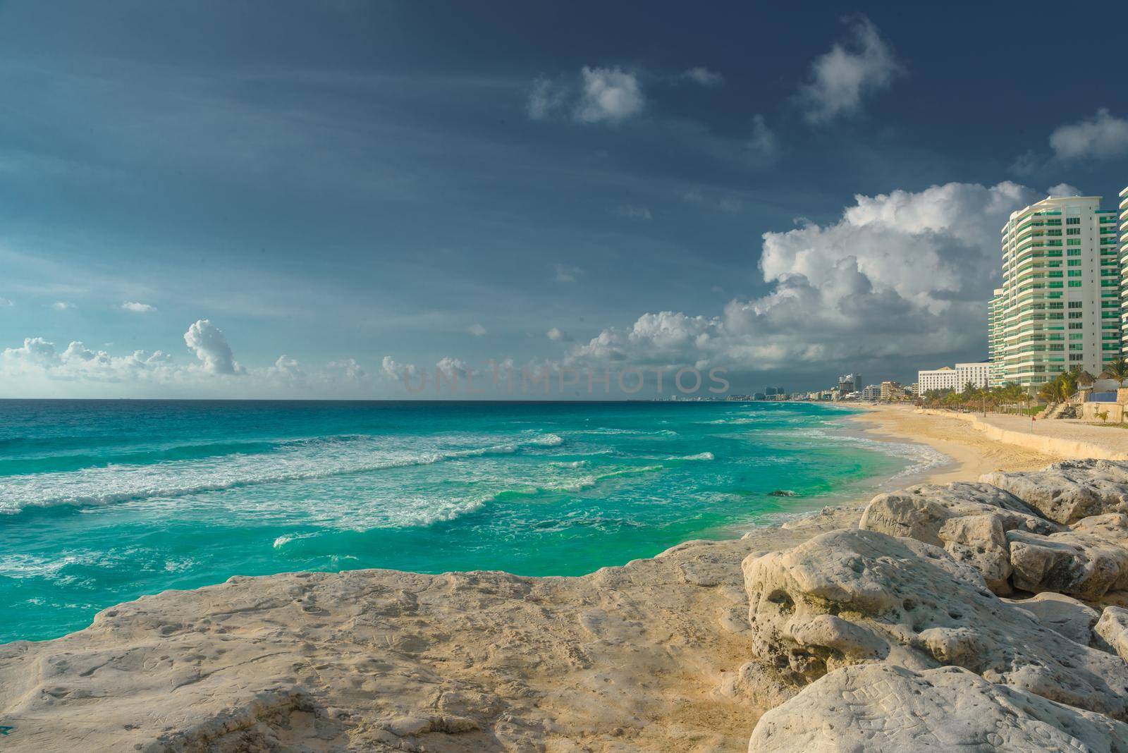 The coastline of the Caribbean Sea with white sand and rocks in Cancun.