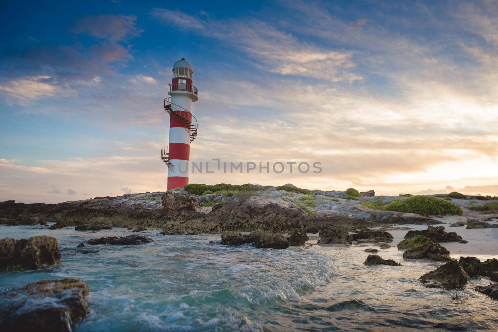 Lighthouse on a rocky shore in Cancun. Clear sky and blue sea.