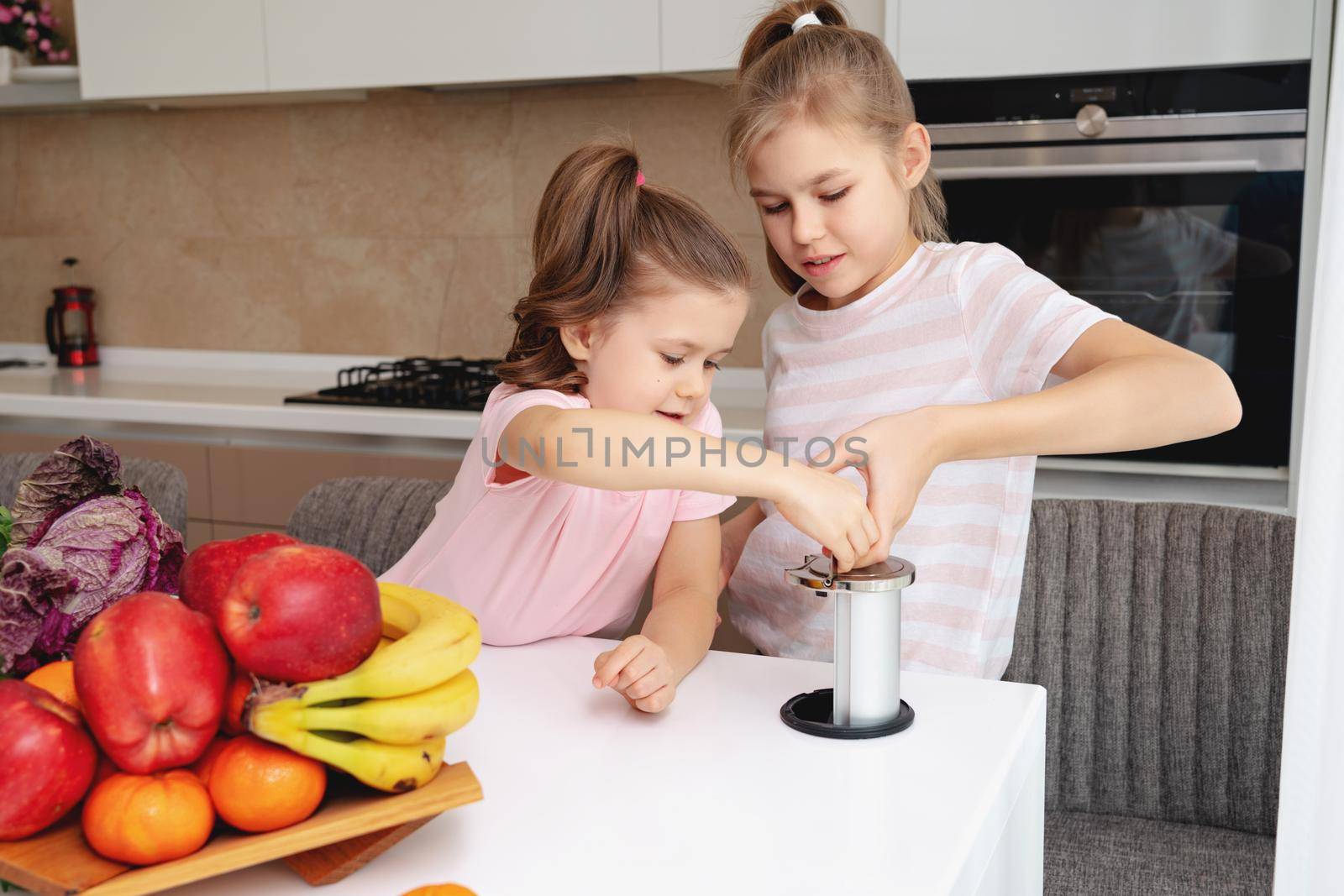 Girls looking at electric outlet on the modern kitchen table by Mariakray