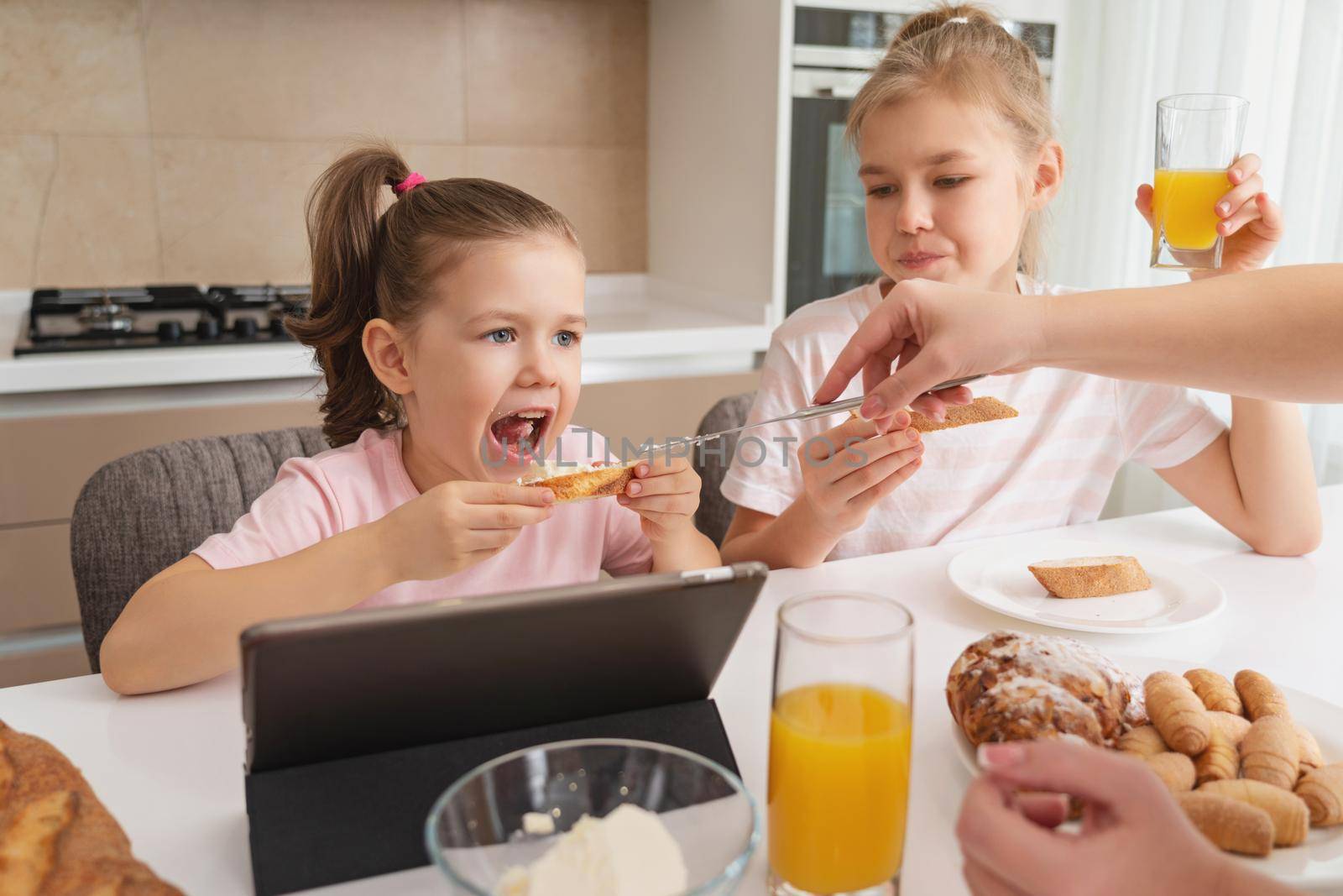 Mother and two daughters having breakfast together, happy single mother concept