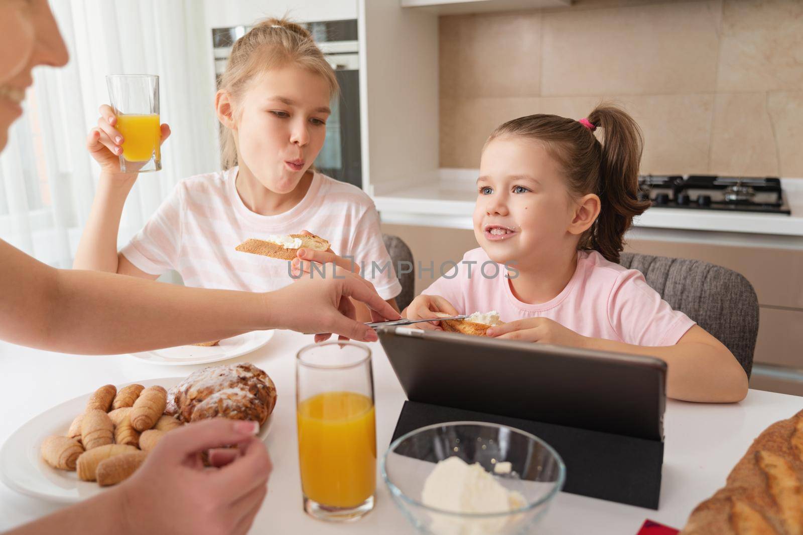 Mother and two daughters having breakfast together, happy single mother family concept by Mariakray