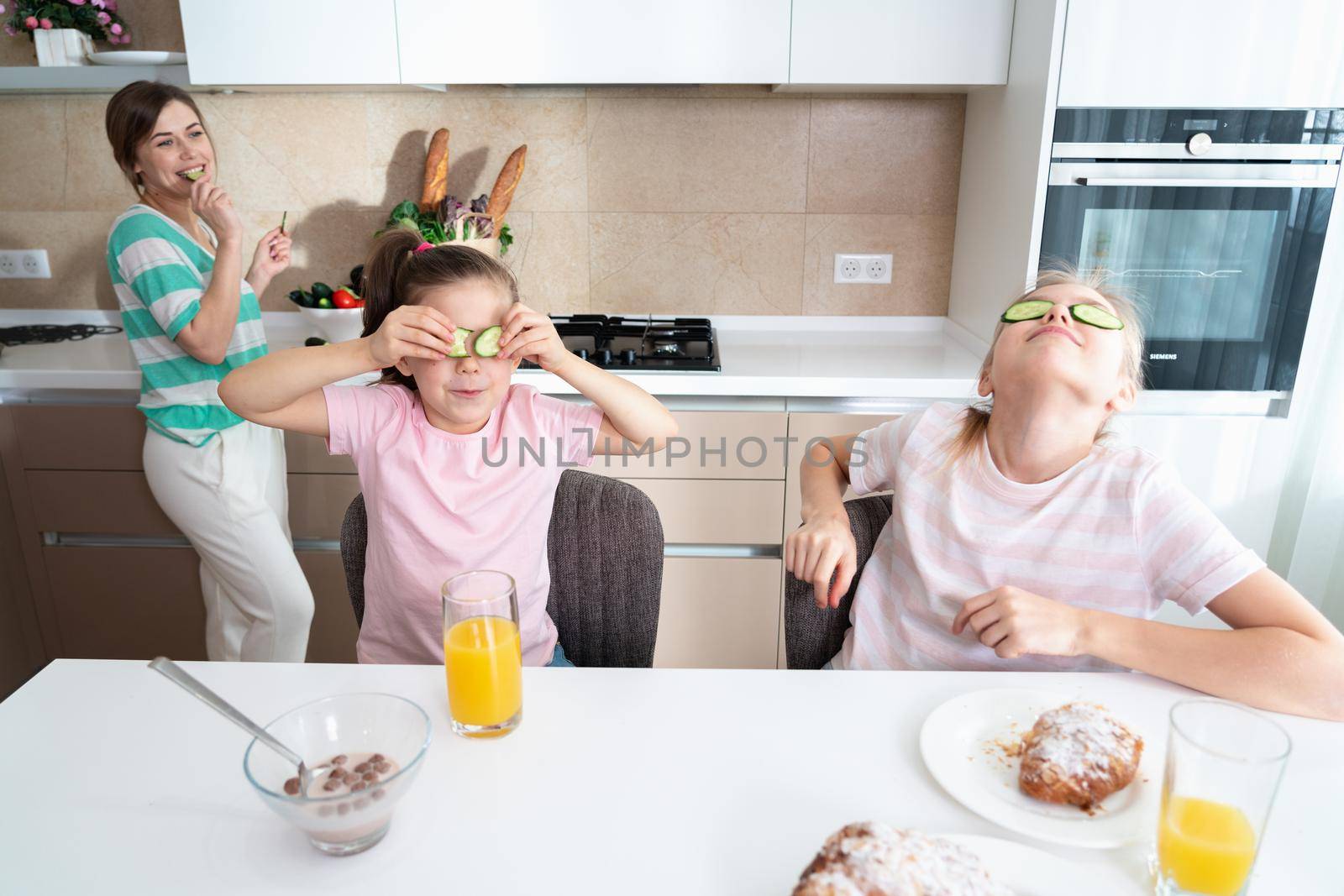 Happy young mother and daughter having fun in kitchen, happy single mother family concept by Mariakray