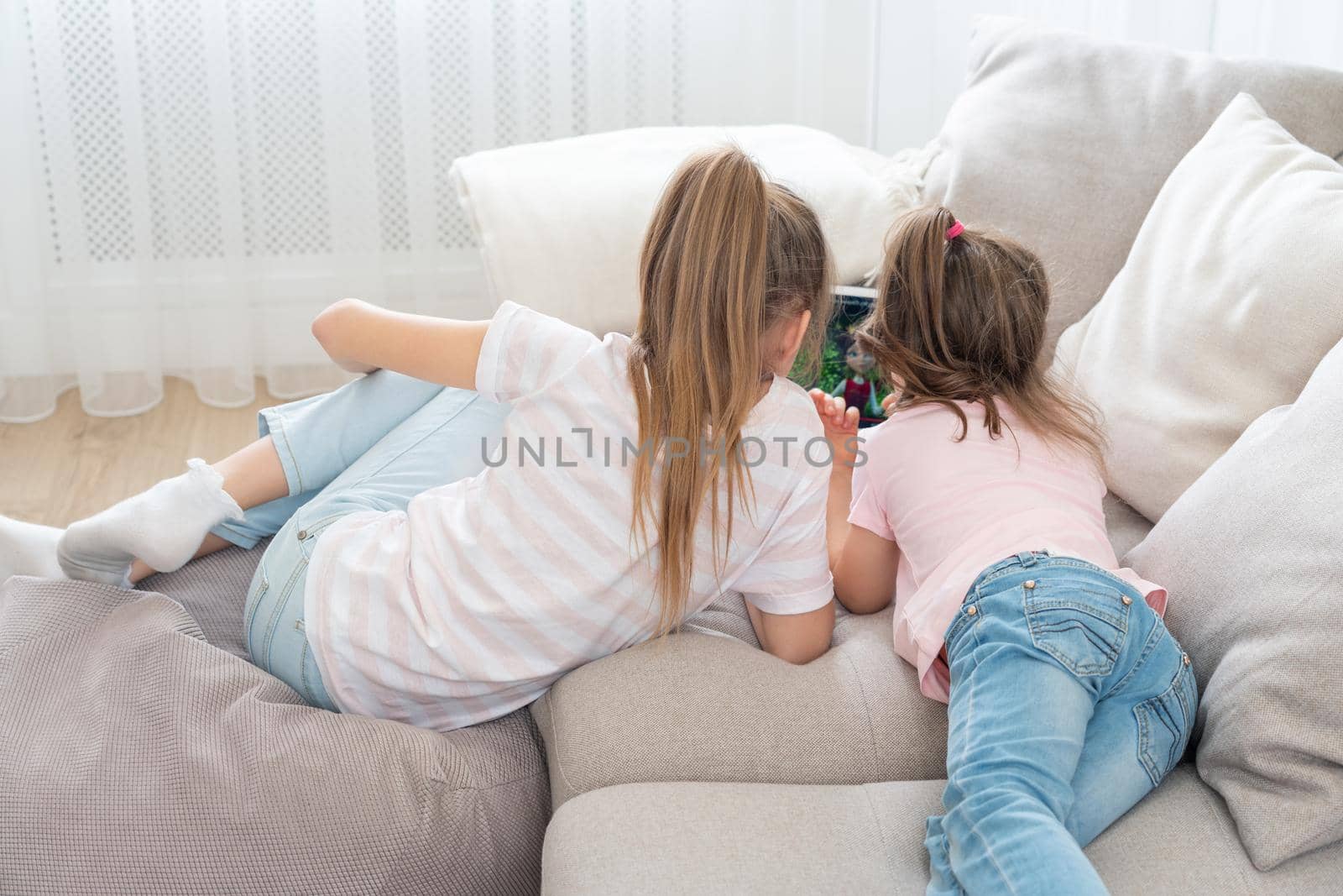 Two sisters Lying On Couch And Using Tablet, top view by Mariakray