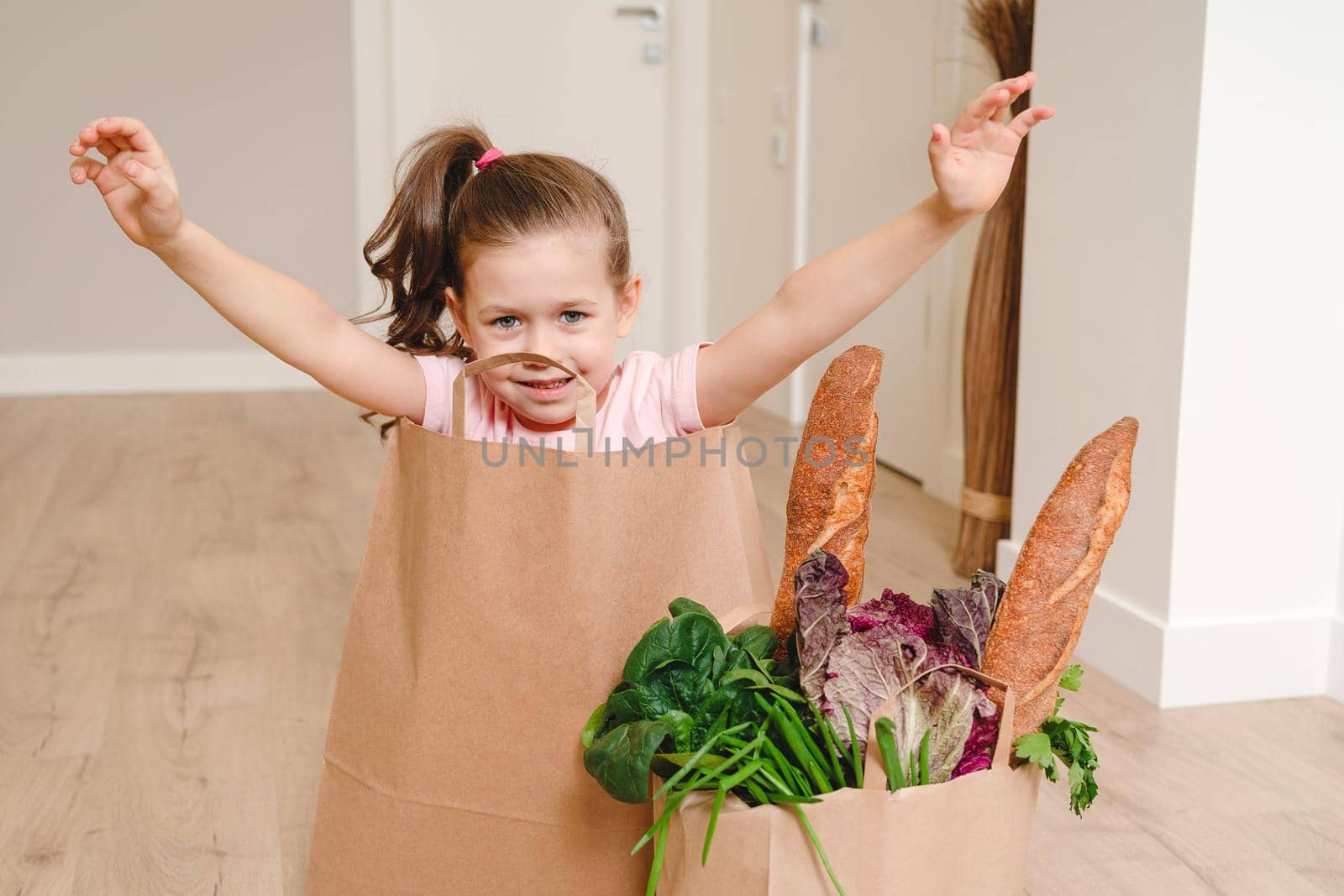 Little girl sitting in Paper bag hiding with vegetables and bread, grocery with copy space by Mariakray