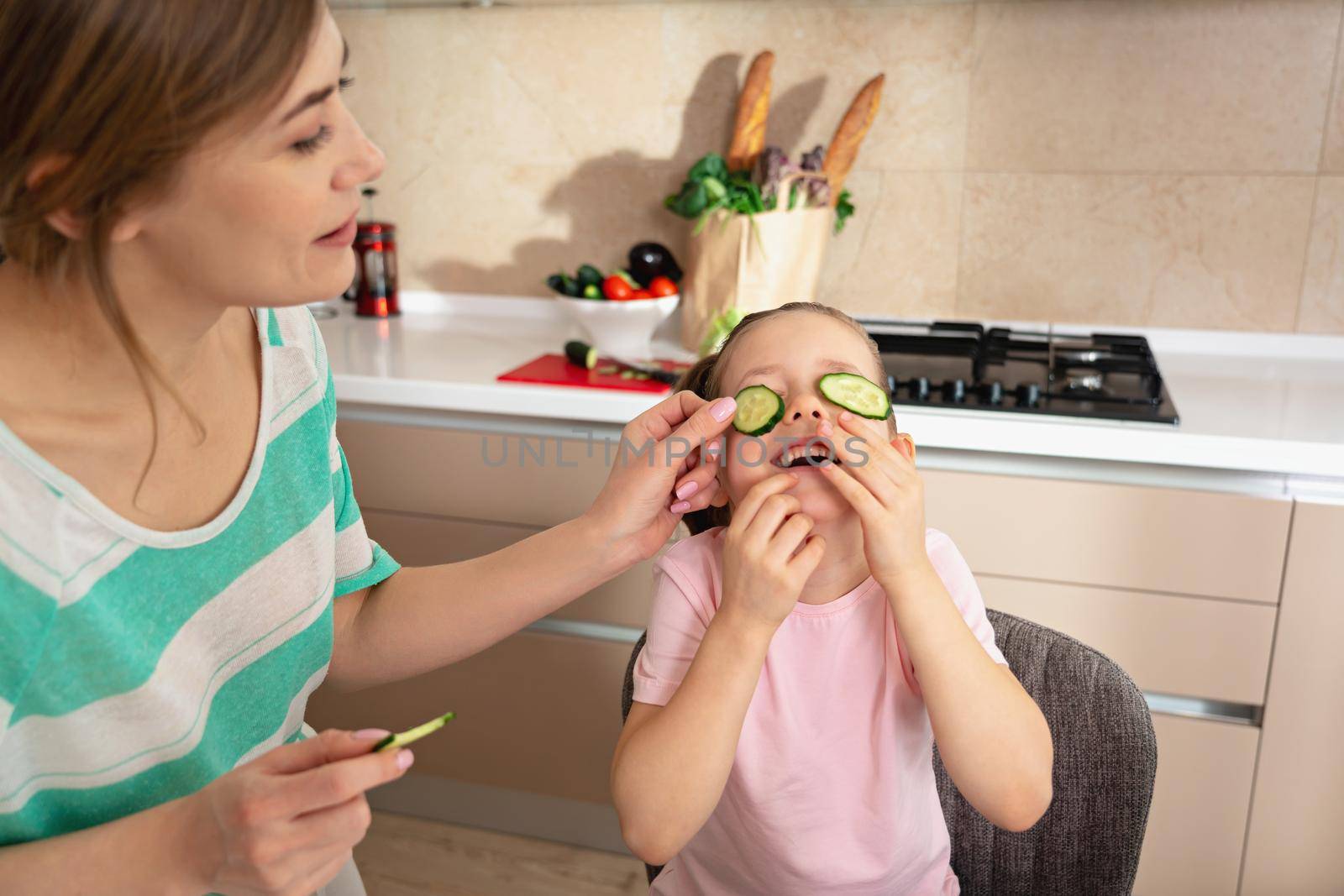 Happy young mother and daughter having fun in kitchen, happy single mother family concept by Mariakray