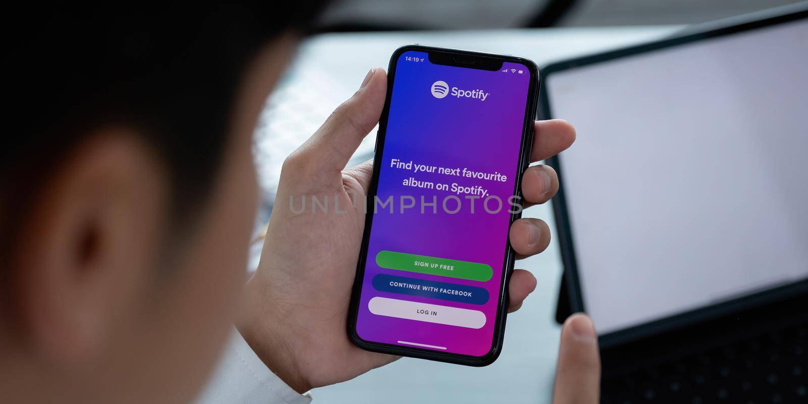 CHIANG MAI, THAILAND - APR 06, 2021: Person holding a brand new Apple iPhone XS with Spotify logo on the screen. Spotify is a popular commercial music streaming service by nateemee