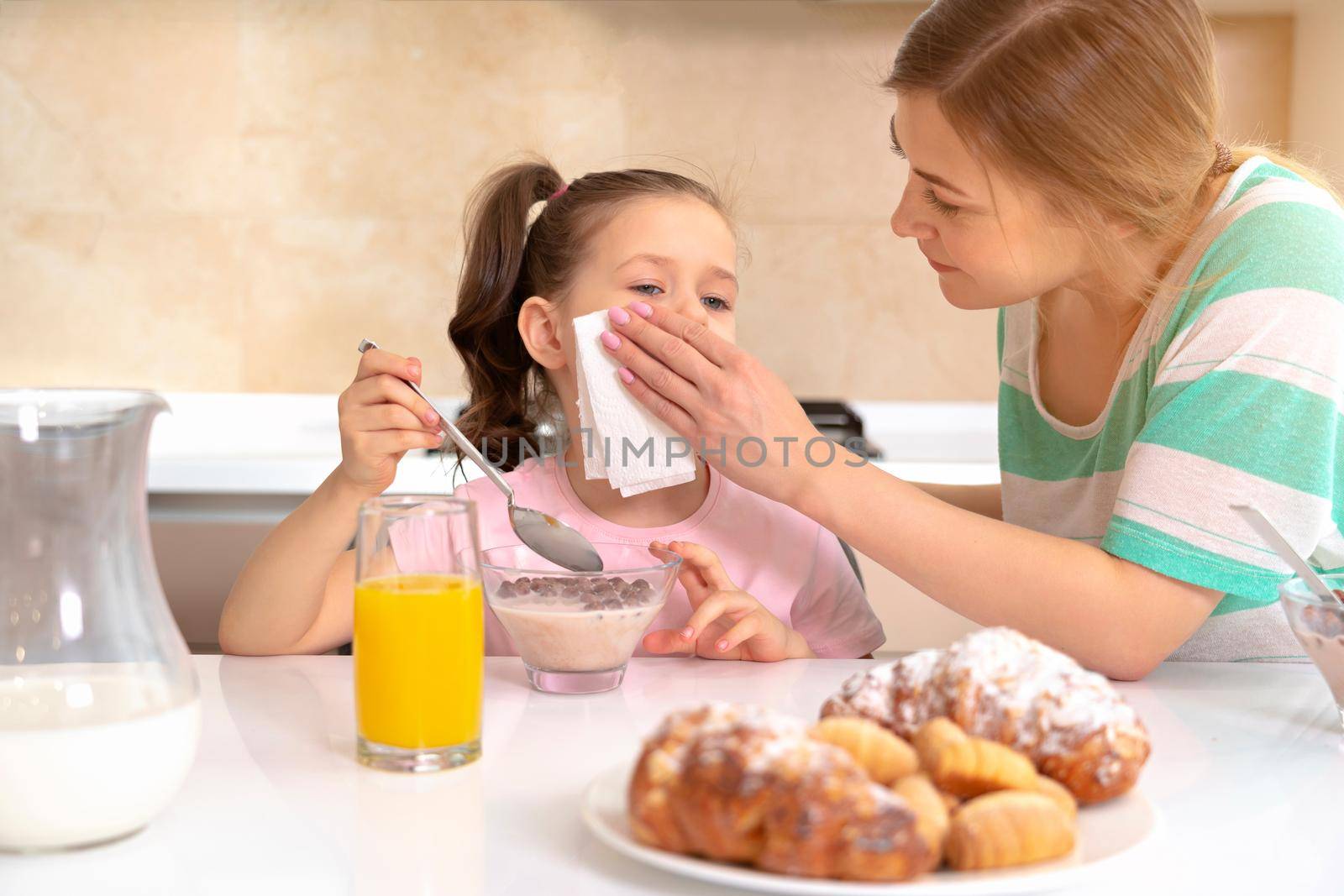 Mother serving breakfast to her two daughters at a table in kitchen