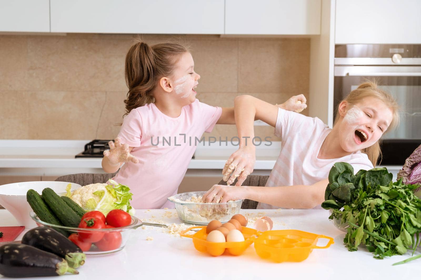 happy family funny kids are preparing the dough, bake cookies in the kitchen. sisters having fun together laughing by Mariakray