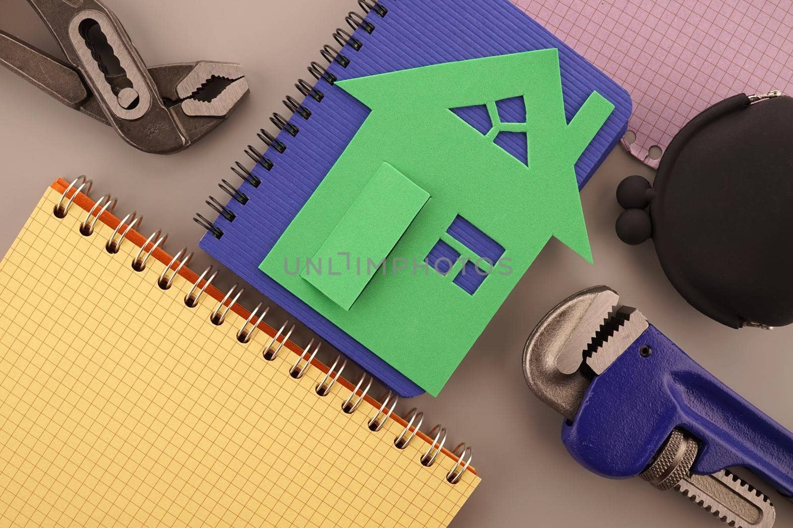 House ownership, building or construction still life concept with a flat lay of notebooks, wrench, purse, pencil and colorful cutout paper homes