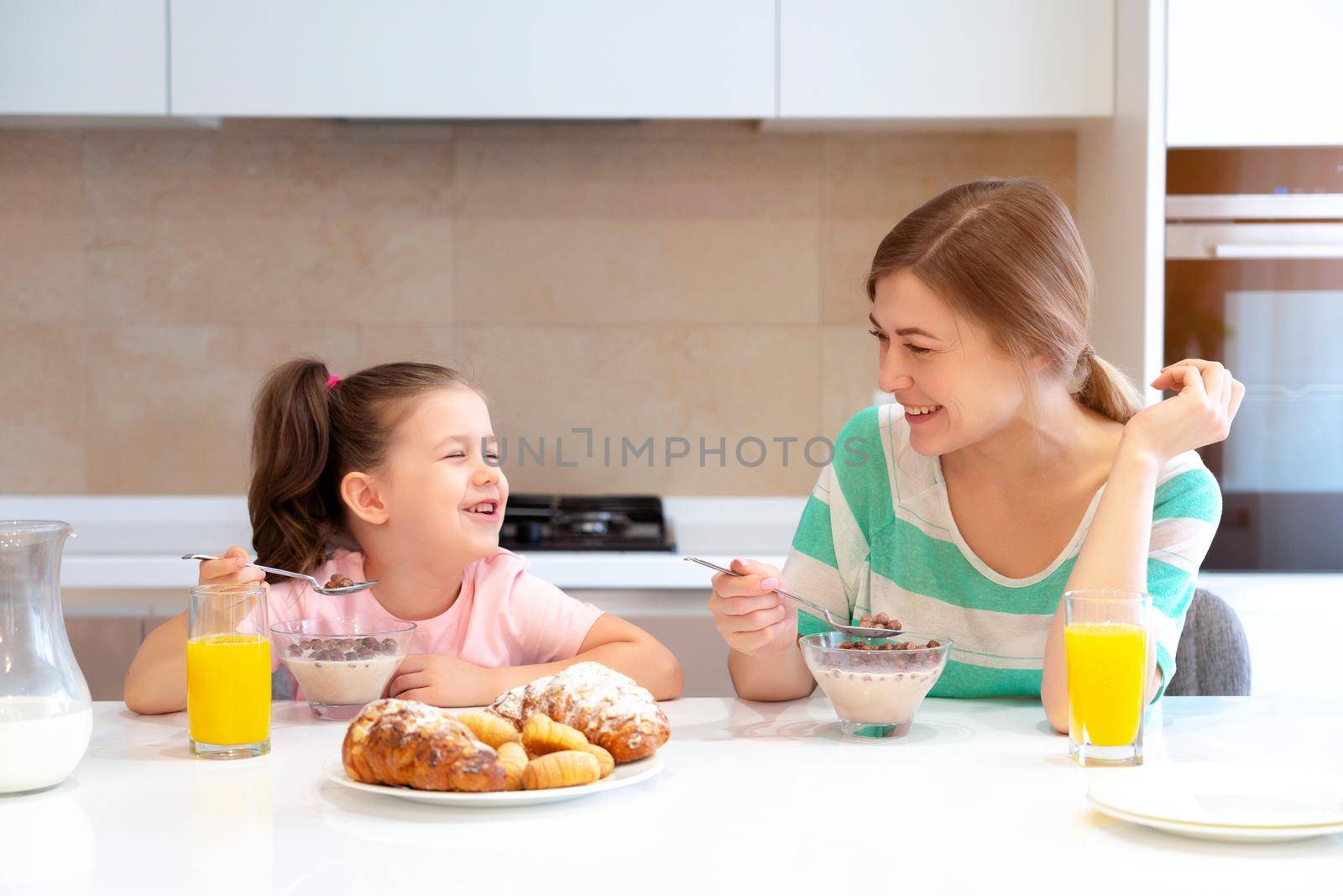 Mother serving breakfast to her two daughters at a table in kitchen