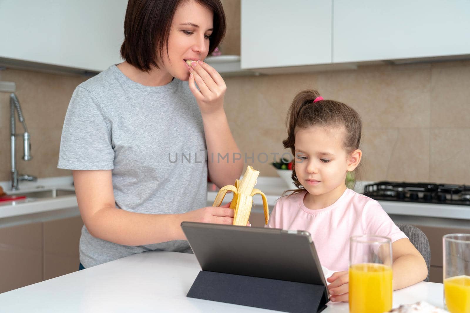 Mother feeding daughter with banana at the table