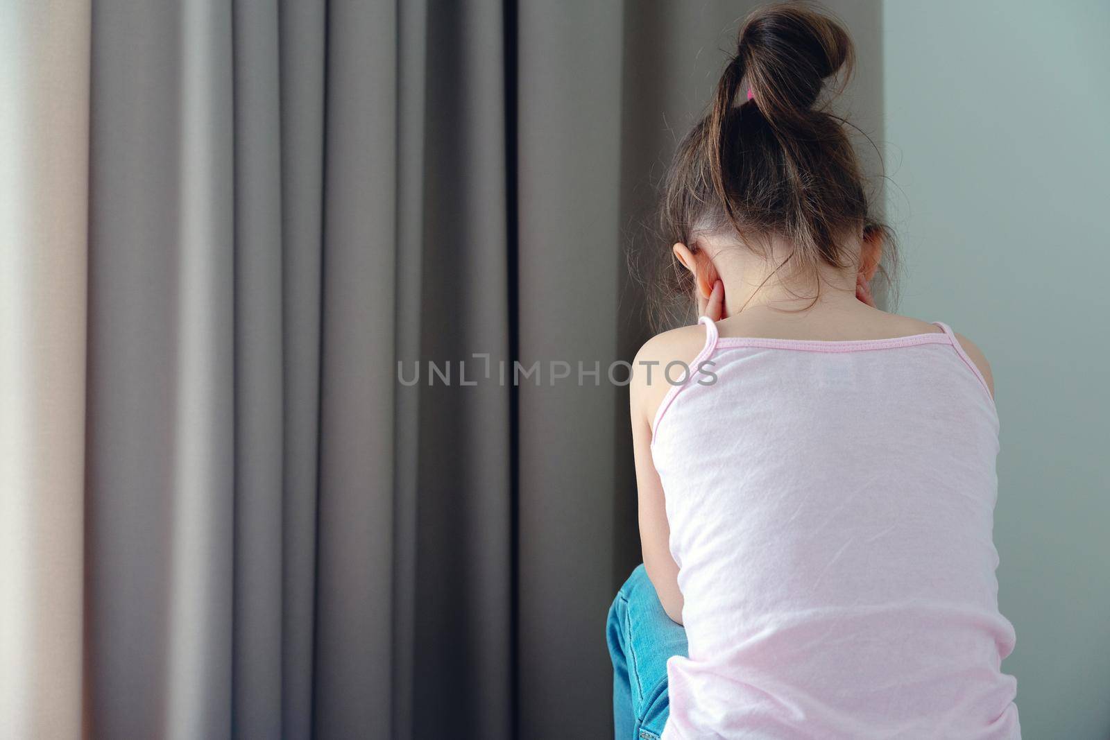 A little sad girl sitting on a bed, back view by Mariakray