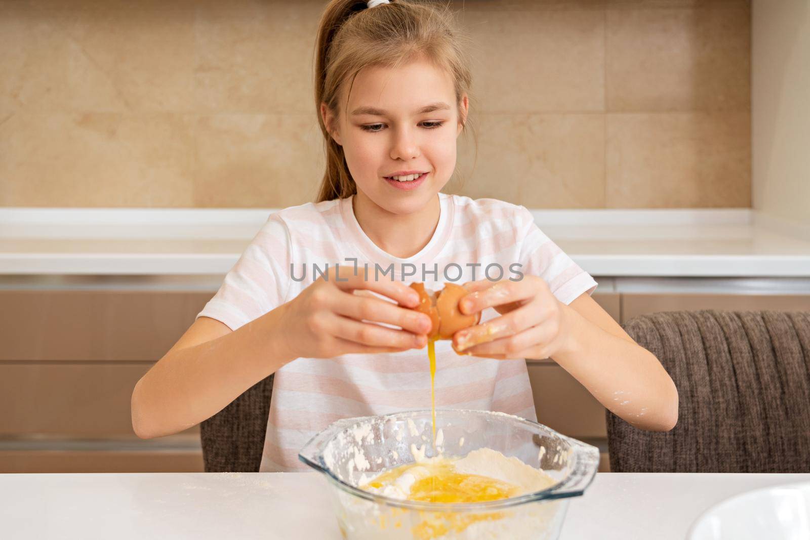 Little girl cracking egg to make cookies