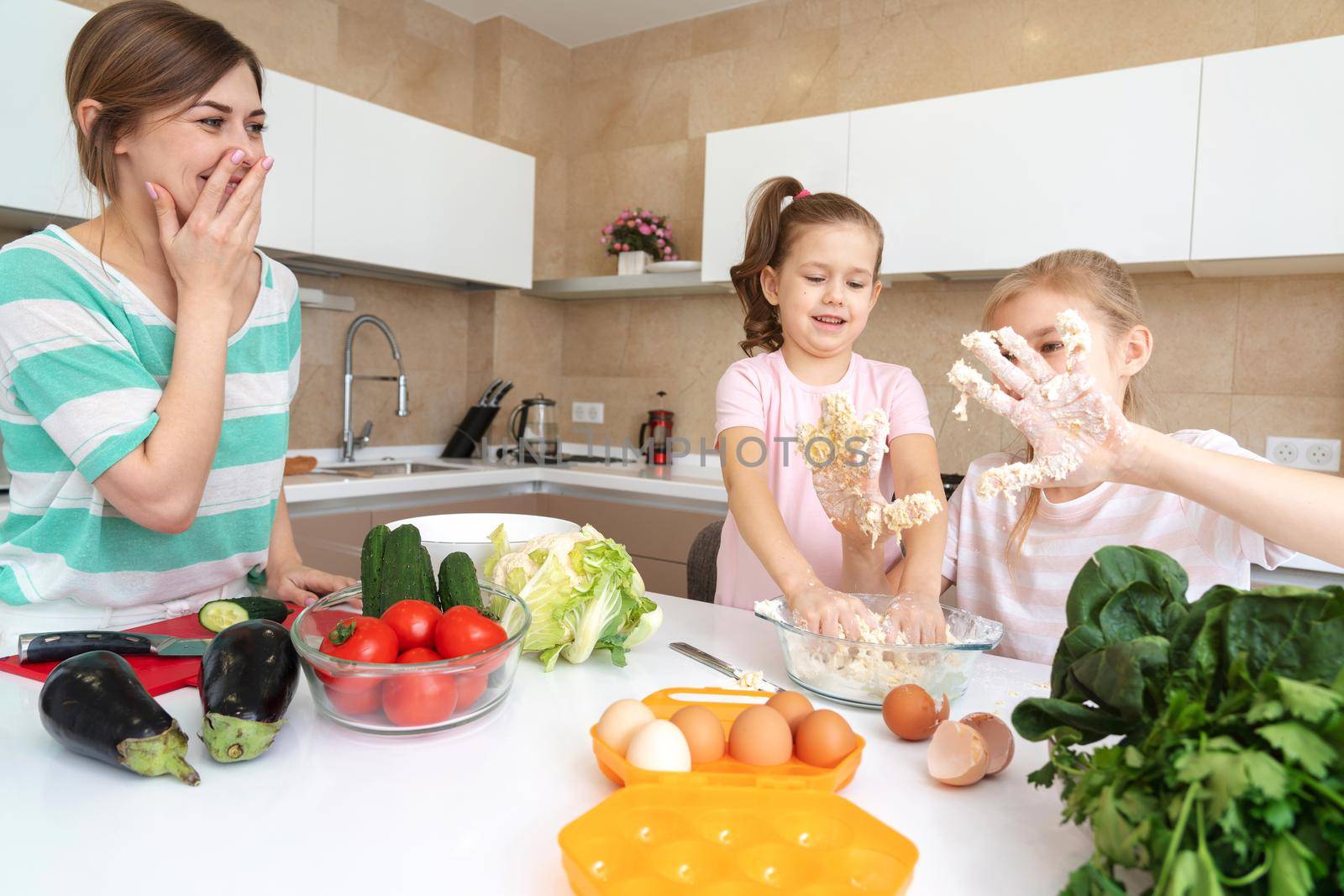 Mother and two daughters cooking in the kitchen and having fun, happy family and single mother concept by Mariakray