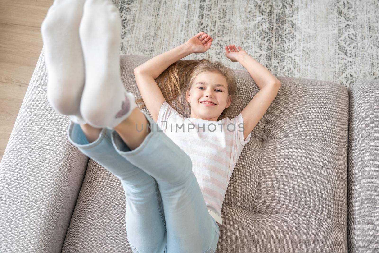 Preteen girl lying on couch with bare feet raising up high