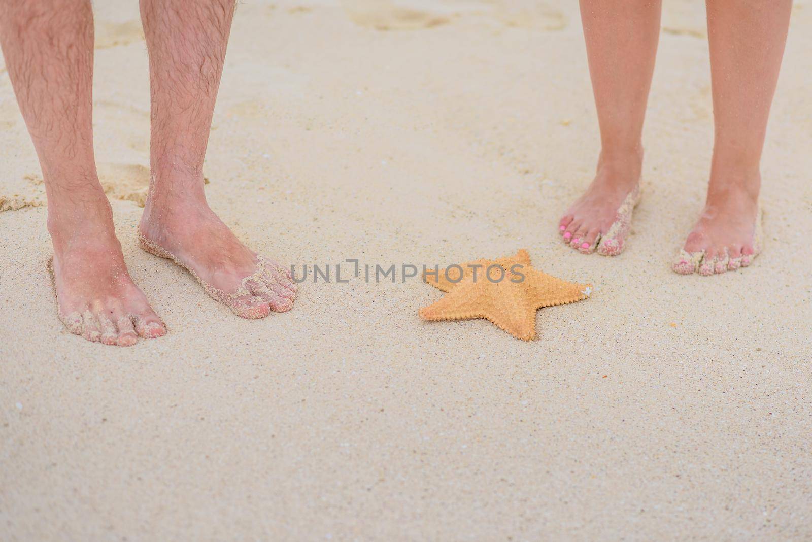 Two pairs of legs and starfish on white sand. by Kai_Grim