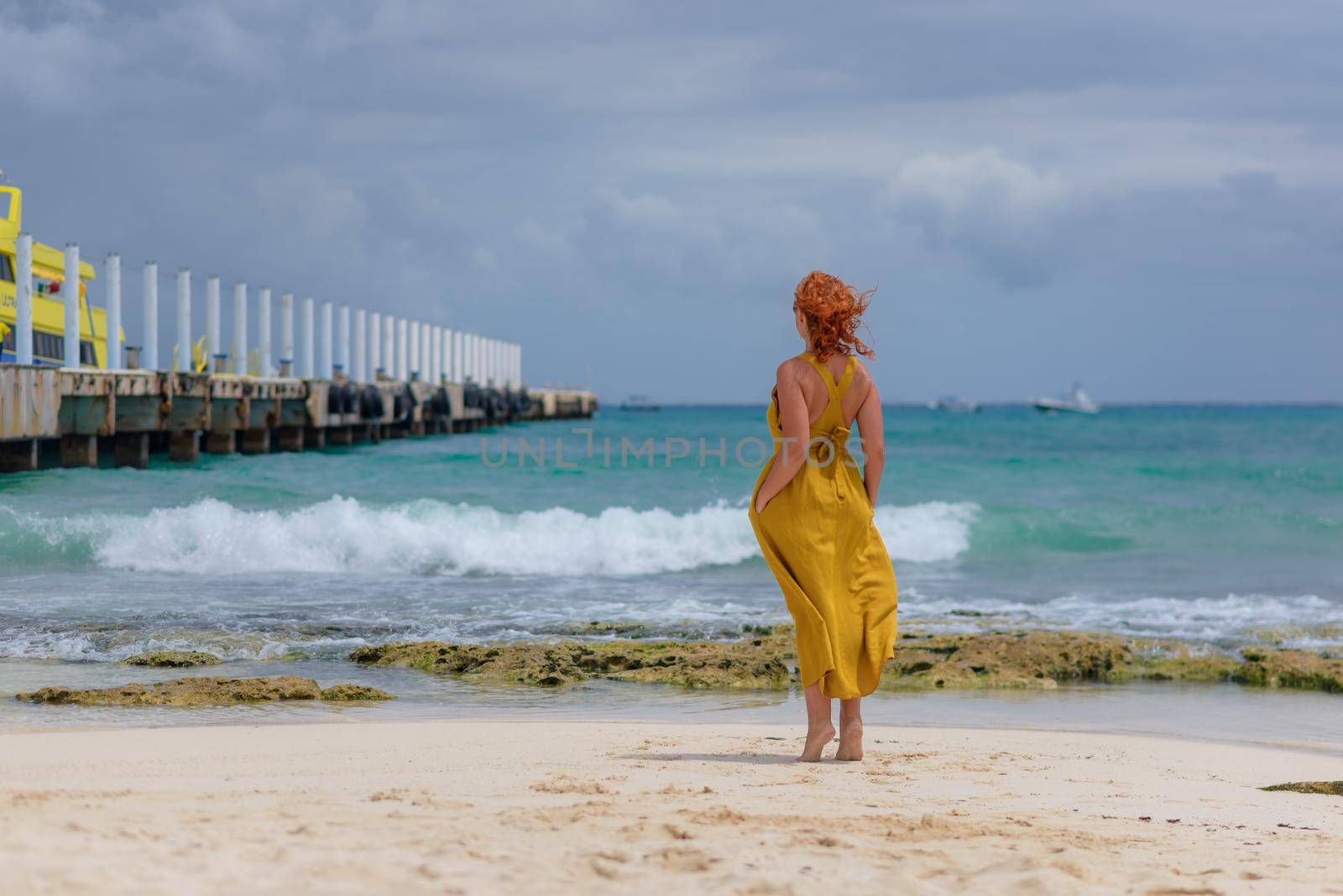 A woman on the beach looks at the horizon and walks along the beach. Mexico.