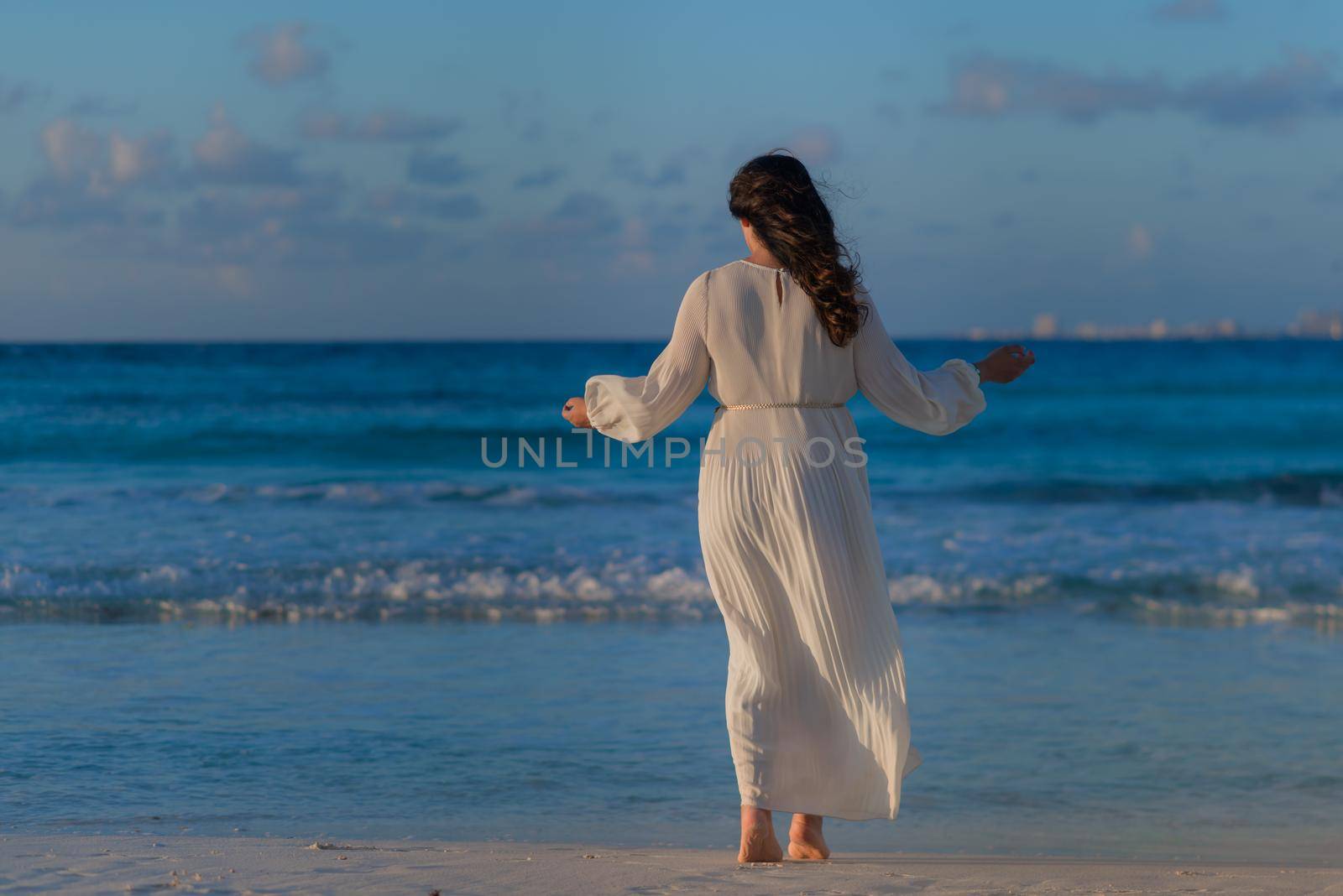 A woman on the beach looks at the horizon and walks along the beach. Mexico.