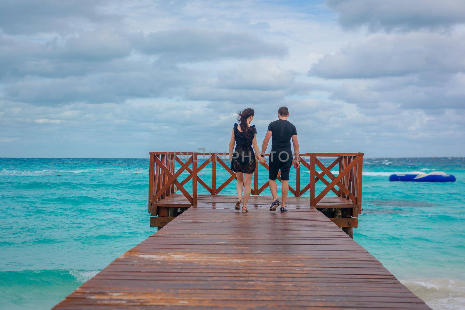 A man and a woman walk on the pier by the sea.