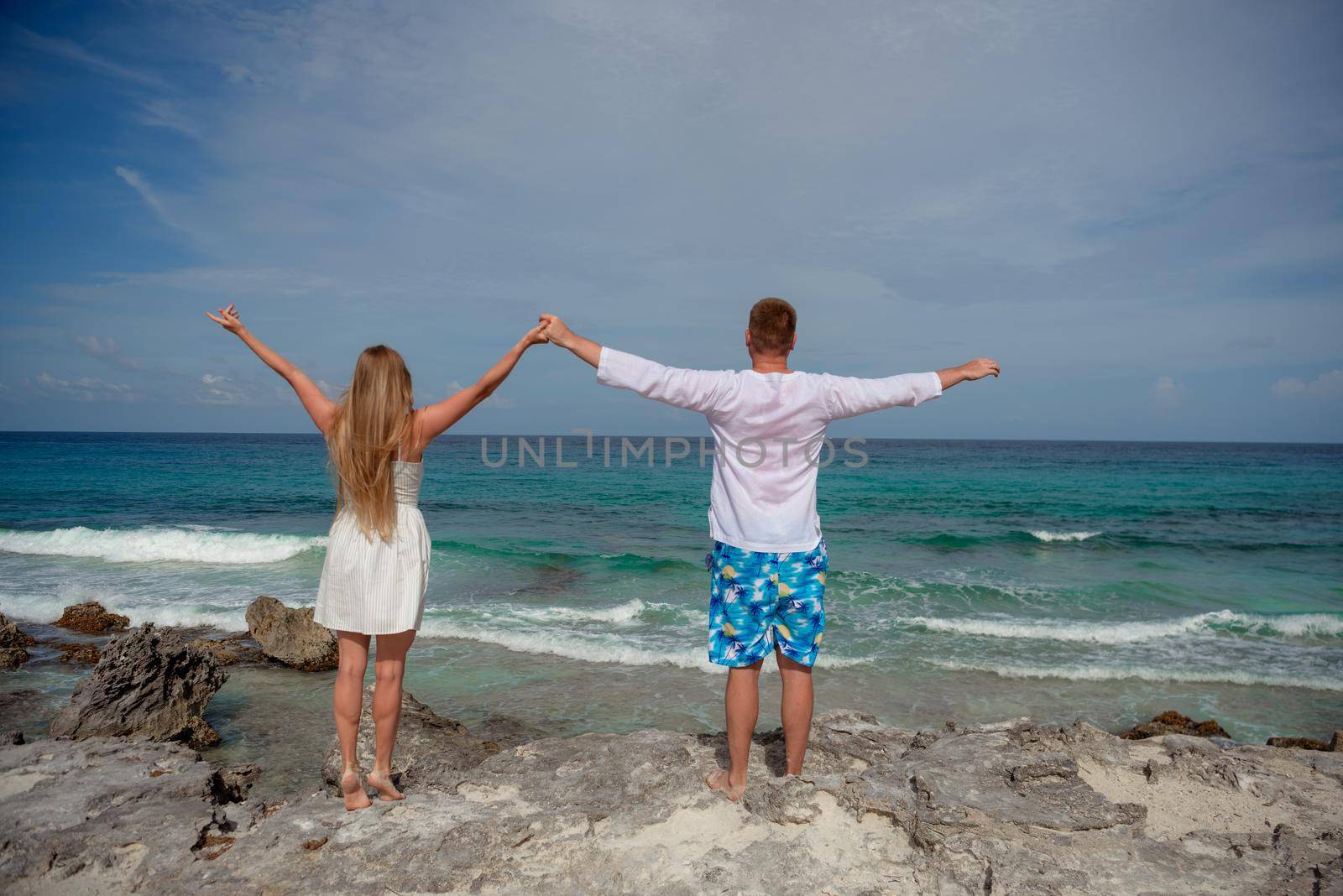 A man and a woman walk on the seashore.